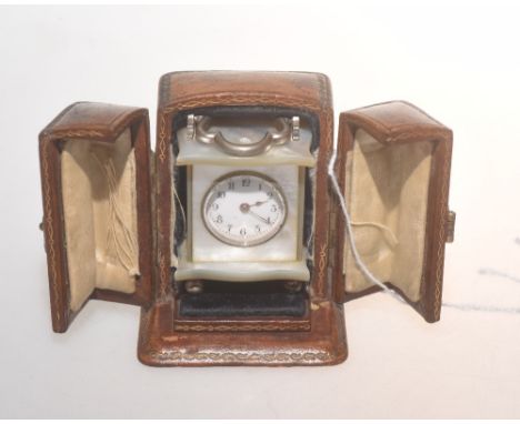 A miniature mother of pearl carriage clock with white enamel face and Arabic numerals, in a gilt tooled leather case.