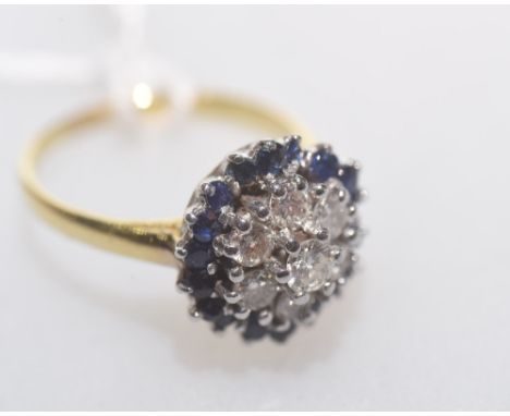 An 18ct gold sapphire and diamond cluster ring, centred by a round brilliant-cut diamond in a domed flowerhead setting. 5.3 g