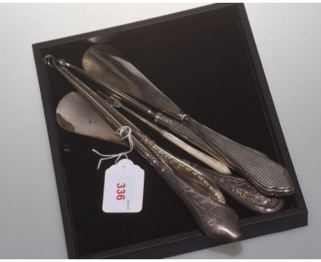A group comprising two silver handled shoe horns, three silver handled button hooks and a mother of pearl handled silver pick