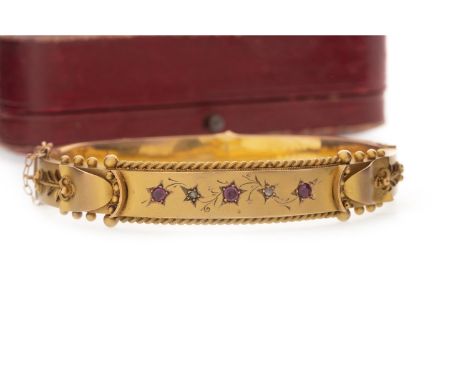 LATE VICTORIAN NINE CARAT GOLD DIAMOND AND GEM SET BANGLE of oval form, the central panel with star set diamonds and red gems