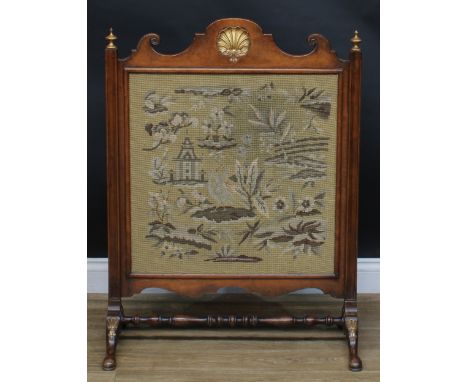 A George II inspired parcel-gilt mahogany fire screen, shaped cresting centred by a shell, woolwork banner, turned stretcher,