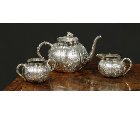 A Chinese silver three piece melon shaped tea service, comprising teapot, milk jug and sucrier, chased with birds and blossom