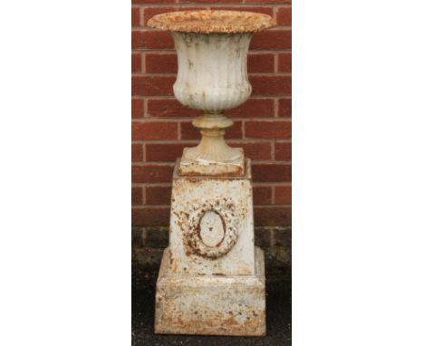 A 19th century cast iron campana shaped garden urn and plinth, egg-and-dart rim, the plinth cast and applied with a ribbon-ti