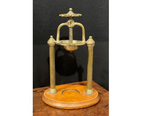 An early 20th century brass citrus fruit juicer, ship's wheel screw action compressor, the pierced basin supported by a pair 