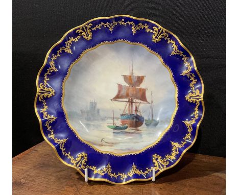 A Royal Crown Derby wavy edged cabinet plate, painted by W. E. J. Dean, signed, the field painted with a ship at anchor, with