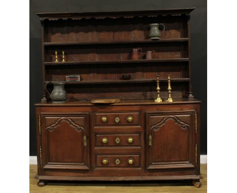 An early 19th century North European oak dresser, moulded cornice above three plate rack shelves, the projecting base with th