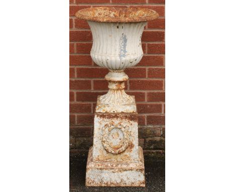 A 19th century cast iron campana shaped garden urn and plinth, egg-and-dart rim, the plinth cast and applied with a ribbon-ti