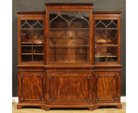 A large George III Revival mahogany break-centre library bookcase, moulded cornice with meandrous capital, above astragal gla