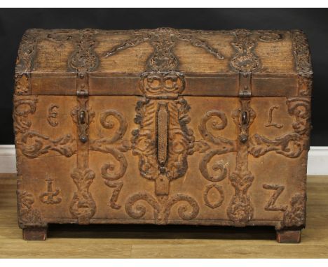 An early 18th century Spanish metal bound chest or trunk, hinged dome top, carry handles to sides, the mounts cast as stylise