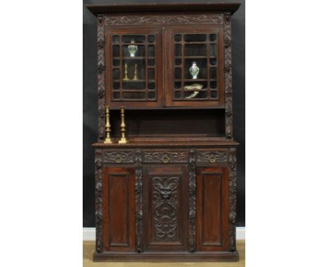 A late 19th century oak library bookcase, outswept cornice with gadrooned capital above a pair of glazed doors enclosing two 