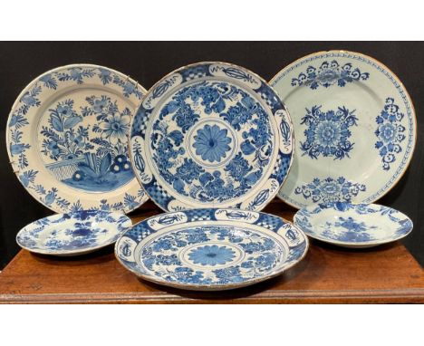 A pair of Delftware chargers, boldly decorated in underglaze blue with flowers, 34.5cm diameter; others similar, various size