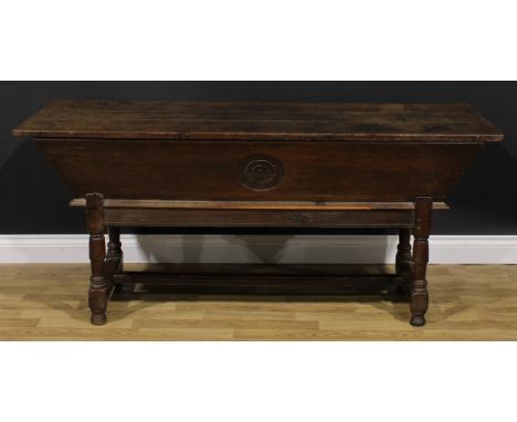 An 18th century joined oak dough bin or proving trough, three plank top, the side carved with a floral roundel, turned legs, 
