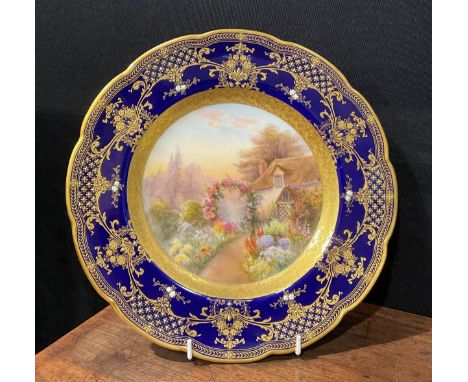 A Royal Worcester shaped circular cabinet plate, painted by R. Rushton, signed, the field with English country cottage in flo