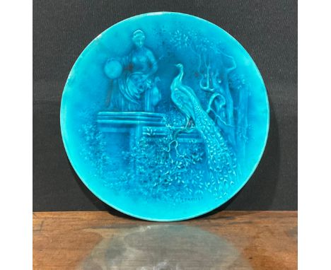 A Burmantofts Faience circular wall plaque, decorated in low relief with peacocks in stately garden, glazed throughout in tur
