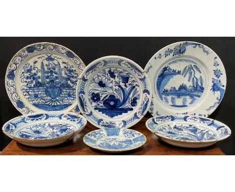 A set of three Delftware chargers, boldly decorated in underglaze blue with flowers, 30.5cm diameter; others similar, various