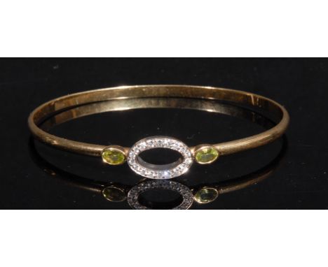 A diamond and peridot hoop bangle, the central oval ring of brilliant cut stones flanked by two oval cut bezel set peridots, 