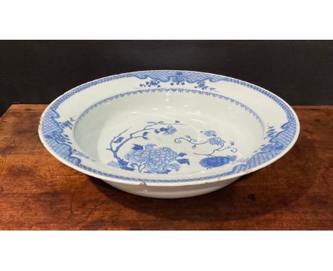 An 18th century Chinese circular basin, painted in tones of underglaze blue with flowers and fruit, the border with panels of