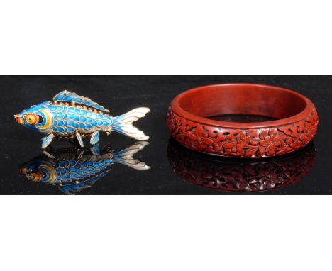 A Chinese cinnabar lacquer bangle, 8.5cm diam; an enamel articulated model, of a fish, 7.5cm long (2) 