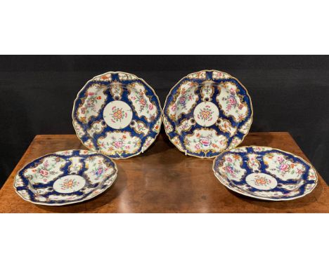 A set of four Worcester shaped circular plates, painted with flowers and sprigs within gilt fan and vase shaped cartouches, o