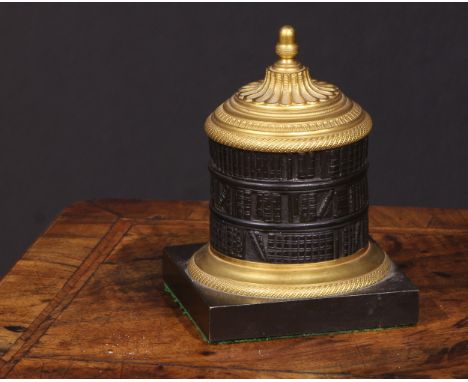A Regency dark patinated and gilt bronze cylindrical library inkwell, cast as a rotunda bookcase, acorn finial, square base, 