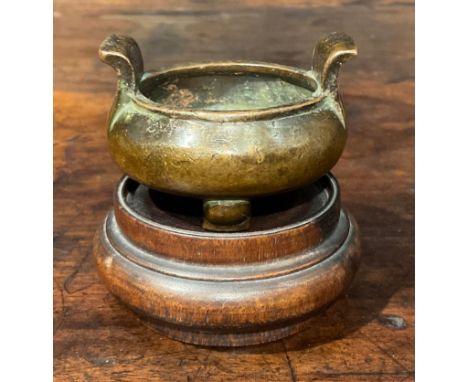 A Chinese copper alloy tripod censer, of small proportions, scroll handles, 5.5cm wide, seal mark, 19th century, hardwood sta