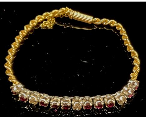 A unusual ruby and diamond bracelet, the three brilliant cut diamonds flanked and divided by 10 rubies, set in a white metal 