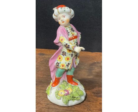A Derby Patch Mark figure, of a Turk, he stands in dancing pose, wearing a fur-trimmed turban and long rode, 12cm high, c.178