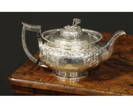 A George III Irish silver teapot, chased with chased with flowers and stiff leaves on a scale ground, ovolo rim, skirted base