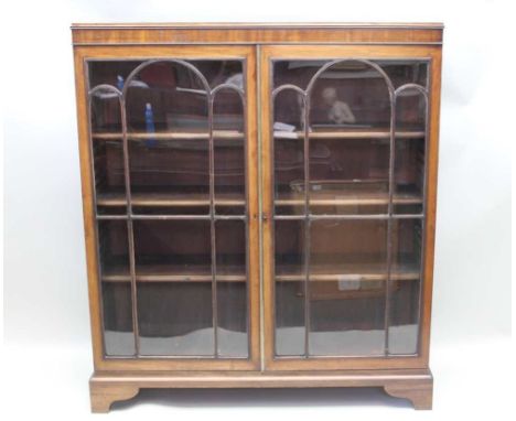 A FIRST QUARTER 20TH CENTURY MAHOGANY FINISHED FREESTANDING BOOKCASE, with twin fancy bar glazed doors, opening to reveal ful