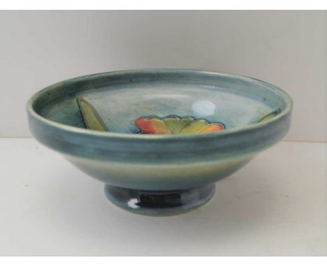 A MOORCROFT FOOTED CERAMIC BOWL, tube lined and painted iris design, on a mottled green ground, 11cm in diameter, with paper 