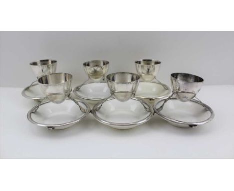 A SET OF SIX CHRISTOPHER DRESSER DESIGN EGGCUPS, the plated frame stamped for 'Hukin and Heath', with white Royal Doulton gla