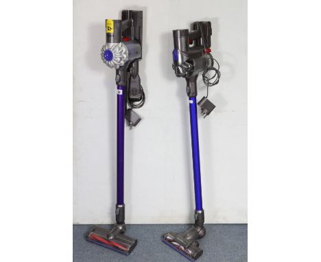 Two Dyson cordless stick vacuum cleaners.