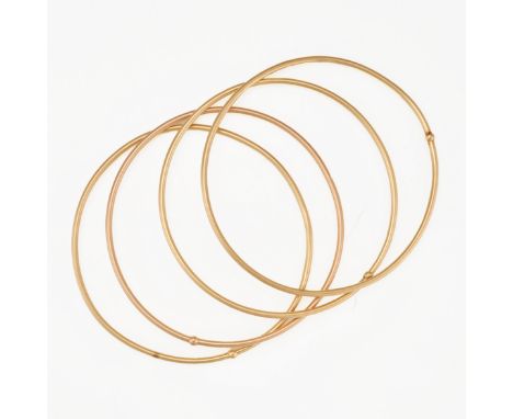 A SET OF FOUR GOLD BANGLES in 18ct yellow gold, each bangle having a singular gold bead intersecting the bangle, each stamped
