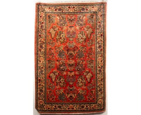 A Sarouk rug, West Persia, the light cranberry field with all over floral sprays framed by an ivory floral vine border, 196cm