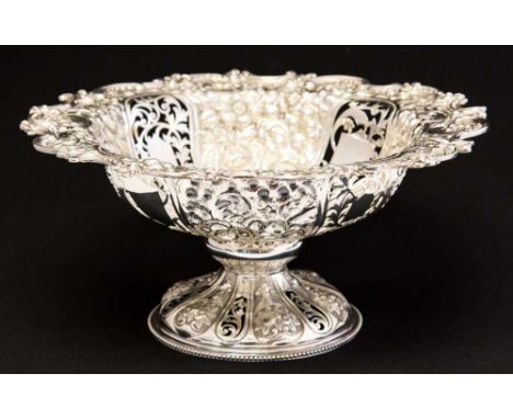 A Victorian silver comport or fruit bowl, heavily embossed and reticulated with pierced foliate scroll cartouches within a fl