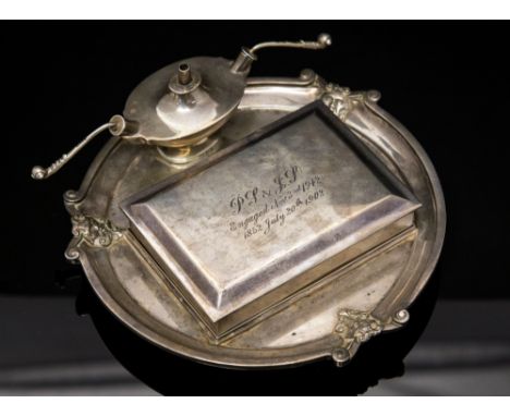 An Edwardian silver smoking companion set, comprising tray, cigarette box and lighter in the form of a lamp, maker Goldsmiths