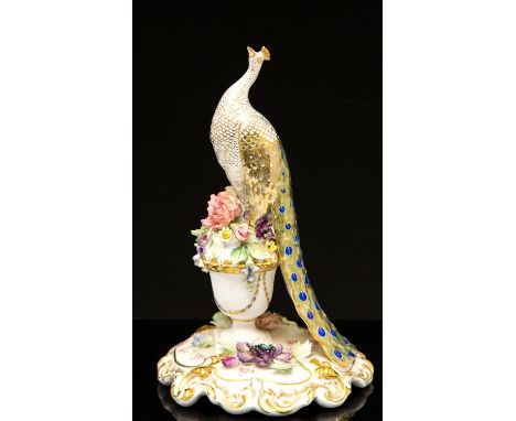 A Royal Crown Derby model of a standing peacock, on a floral encrusted urn, height 26cm, in a presentation box