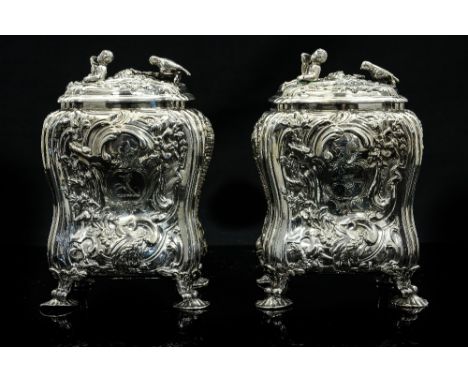 A pair of George II silver tea caddies, ogee form, heavily embossed with Rococo scroll decoration and scenic panels of figure