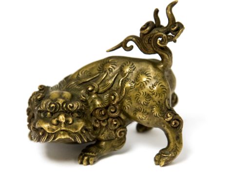 A Chinese miniature model of a Foo dog, modelled crouching, remanents of an old paper label, width 6cm
