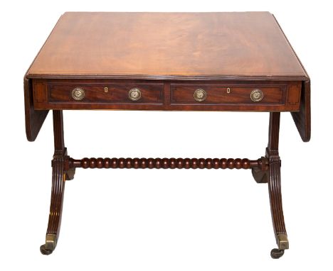 A George V mahogany sofa table, fitted with two drawers, raised on square sectioned supports and standing on sabre legs, bras