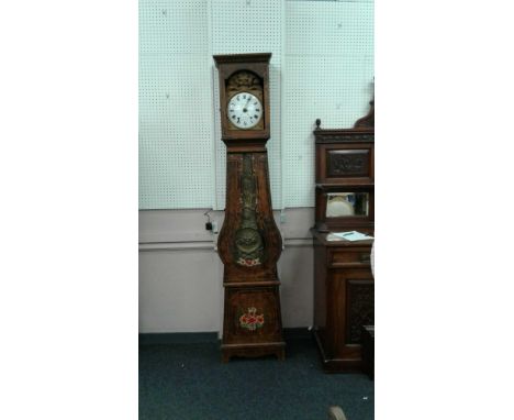 the embossed metal face with circular white enamel Roman numeral dial held in a decorative wooden case with floral patterns, 