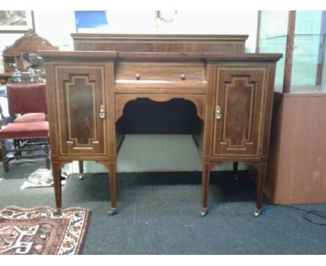 the low back above an inverted breakfront top with inset leather writing surface, above a concave centre drawer flanked by pa
