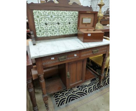 A LATE VICTORIAN TILE BACKED MARBLE TOPPED MAHOGANY WASH STAND WITH TWO DRAWERS ABOVE A CUPBOARD FLANKED BY SHELVES.   W 91 x