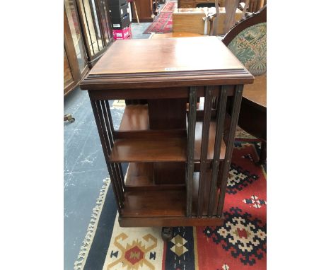 AN EDWARDIAN MAHOGANY ROTARY BOOK CASE, THE CRUCIFORM LEGS ON CASTER FEET. H 90cms W 49cms D 49cm