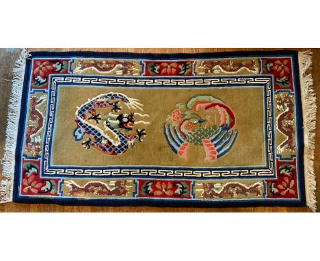 A Chinese rug decorated with a ferocious dragon and fenghuang, on a golden ground, 183 x 95cm.** We would please ask that all