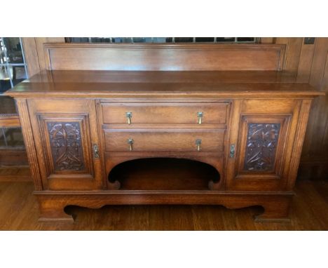 An Edwardian oak sideboard, fitted with two drawers, and two panelled doors, carved with scrolls, 114cm high, 180cm wide, c.1