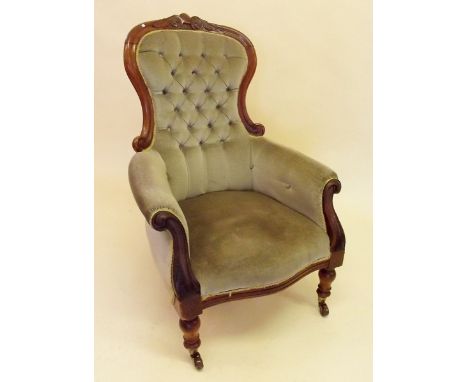 A Victorian mahogany framed button upholstered armchair with scrollwork carved decoration to back and arms
