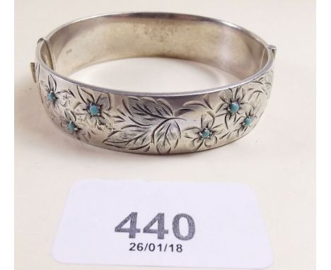 A silver bangle with engraved decoration and inlaid turquoise
