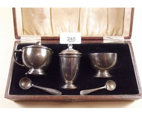 A silver and enamel lined cruet set comprising salt, pepper and mustard with two matched spoons (one spoon not silver) cased,