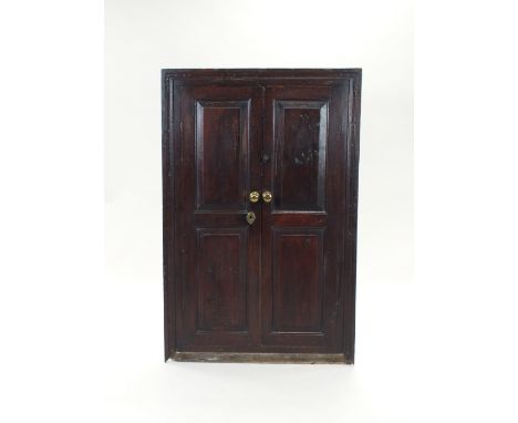 An oak wall hanging corner cabinet, first half 19th century, the two long double fielded panel doors enclosing an arrangement